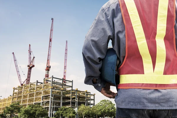 Construction worker checking location site with crane on the background