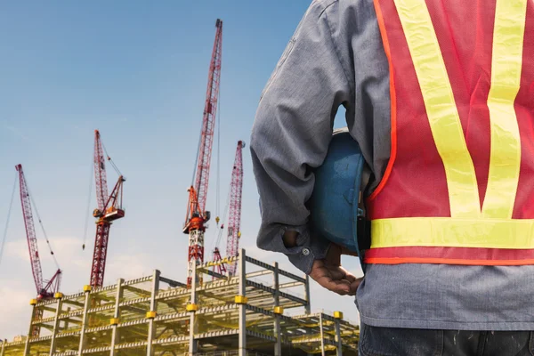 Construction worker checking location site with crane on the background