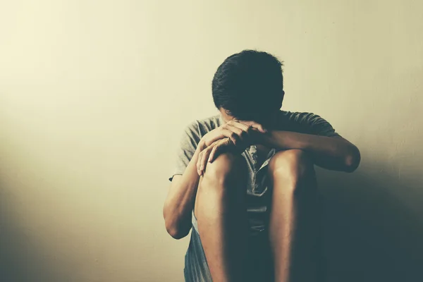 Teenager with depression sitting alone in dark room