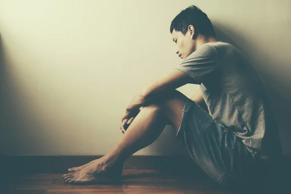 Teenager with depression sitting alone in dark room