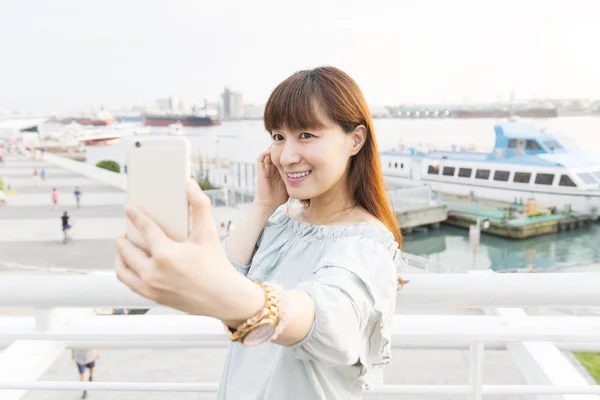 Woman tourist smiling and making travel selfie