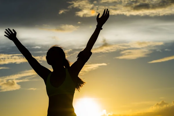 Woman open arms under the sunrise at seaside