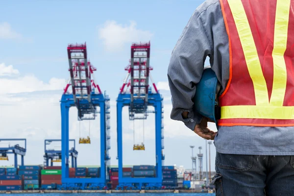 Harbor dock worker talking on radio with ship background