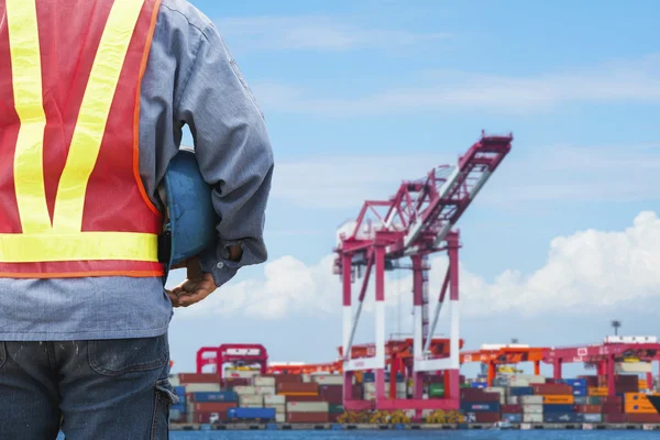 Harbor dock worker talking on radio with ship background