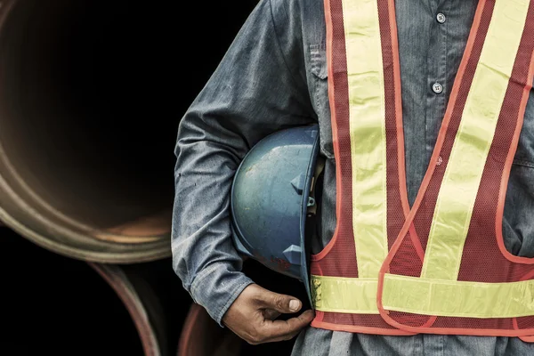 Engineer holding a blue helmet for the safety of workers on the background stock port with cranes and containers