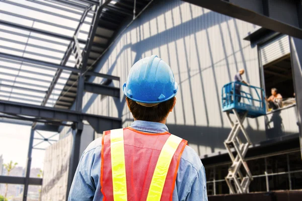 Construction worker checking location site with crane on the background