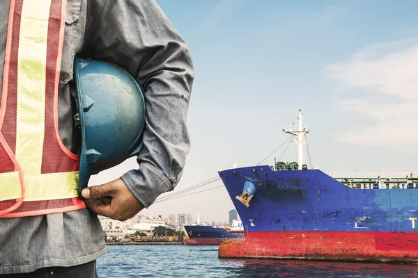 Harbor dock worker talking on radio with ship background