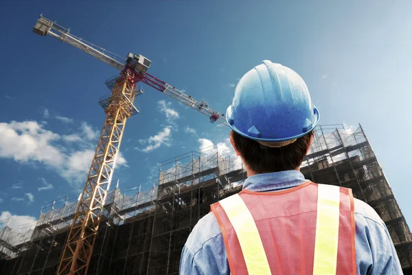 Construction worker checking location site with crane on the background