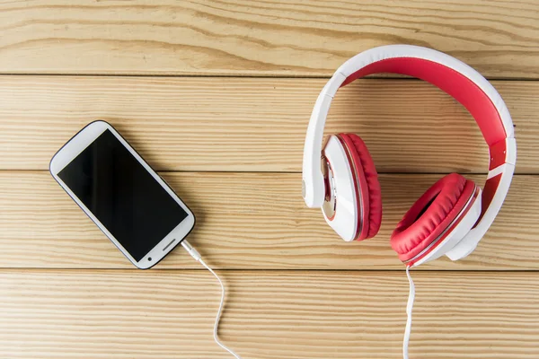 Mobile phone and earphones on wooden background