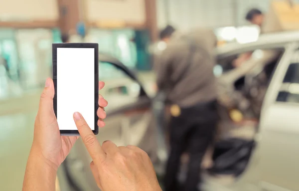 Image of hand holding smartphone and blur technician fixing car