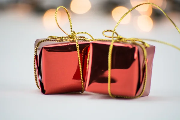 Small red boxes, Christmas ornaments, decorations with gold ribbon on bokeh, light, blurred background