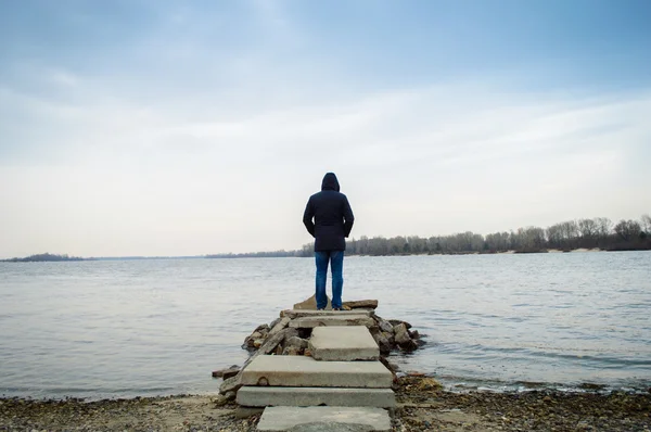 A  man standing alone by the water