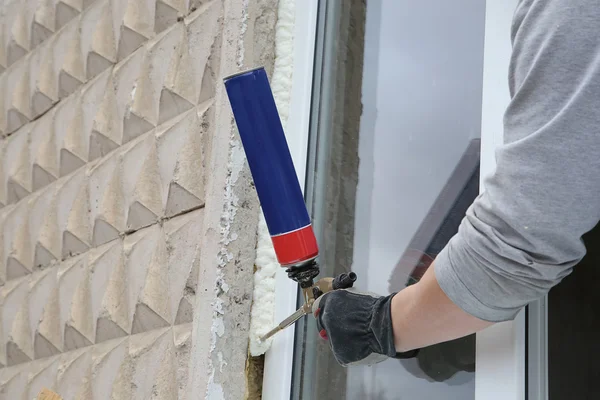 Worker\'s hand fix a window by  polyurethane foam