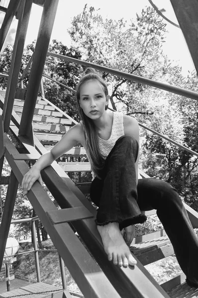 Girl sitting on an iron stairs.