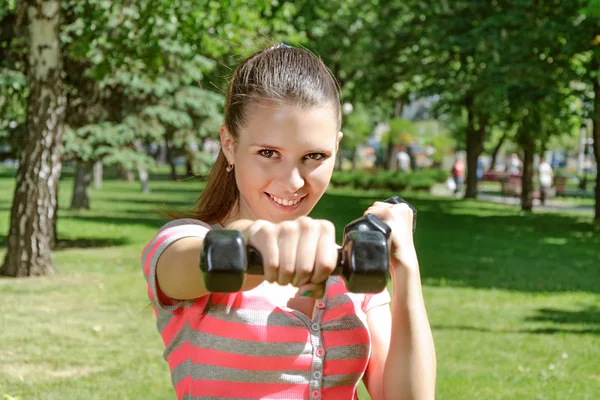 Fitness woman simulates a hit with light dumbbells