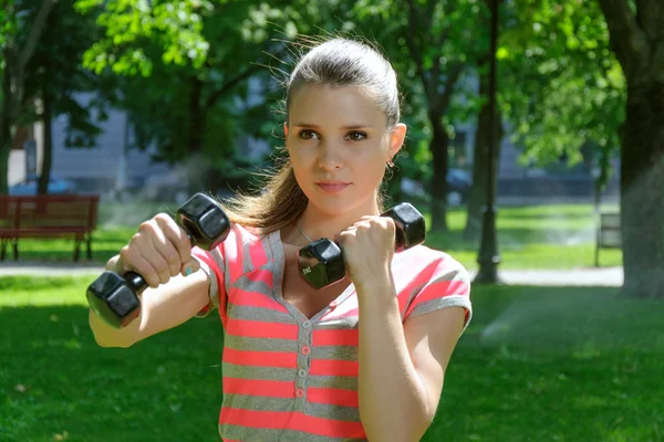 Fitness female simulates a hit with light dumbbells