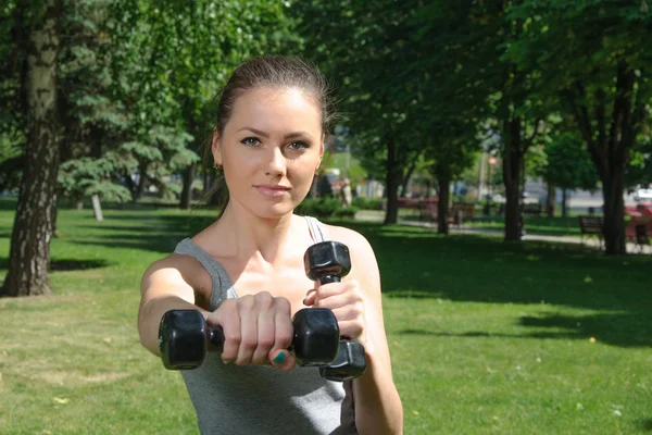 Fitness woman mimics a hit with light dumbbells