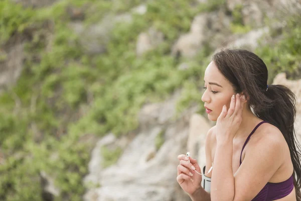 Portrait of young sports woman in fitness outfit listening to music