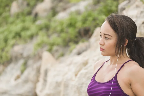 Portrait of young sports woman in fitness outfit listening to music