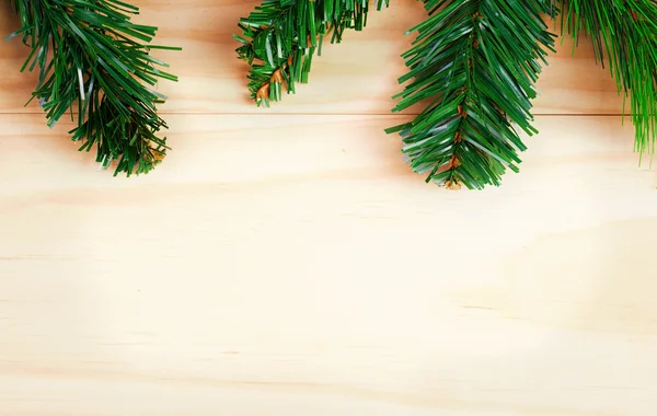Green fir-tree branches on wooden background