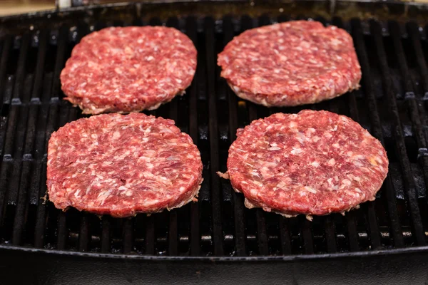 Preparing a batch of  grilled ground beef patties or frikadeller on BBQ