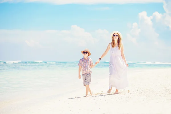 Mother and son walk along the white sand beach having great family holidays time on PAndawa beach, Bali