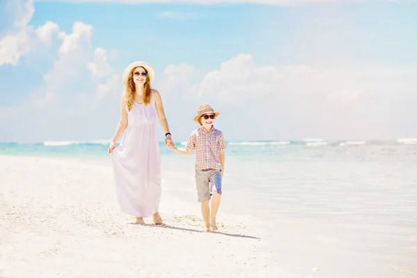 Mother and son walk along the white sand beach having great family holidays time on PAndawa beach, Bali