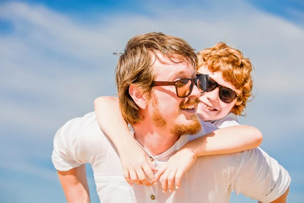 Hipster father with beard and red haired son having happy summer time at a sunny day.