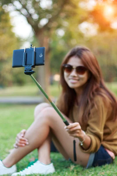 Women hold monopod use smart phone take photograph selfie in park
