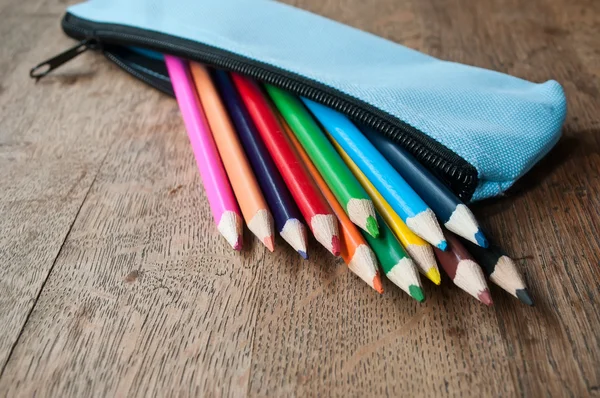 Closeup of colouring pencils in pencil case on wooden background