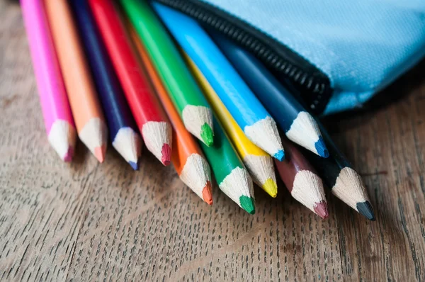 Closeup of colouring pencils in pencil case on wooden background