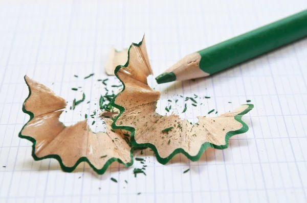 Green pencil and pencil shavings on notebook background