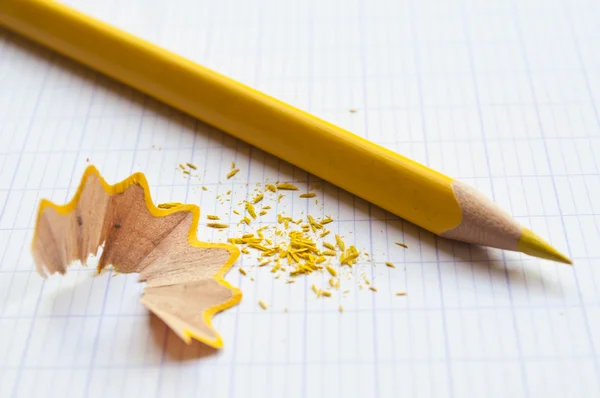 Yellow pencil and pencil shavings on notebook background