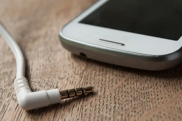 Jack cable and phone on wooden background