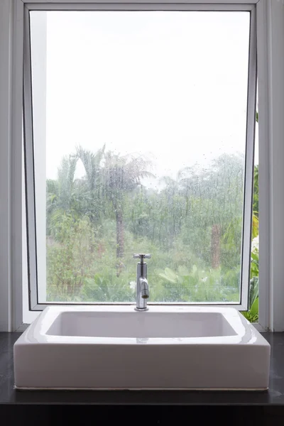 Washbasin in bathroom with transparent mirror window nature view