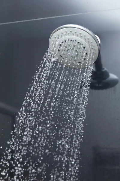 Shower head in bathroom with water drops flowing