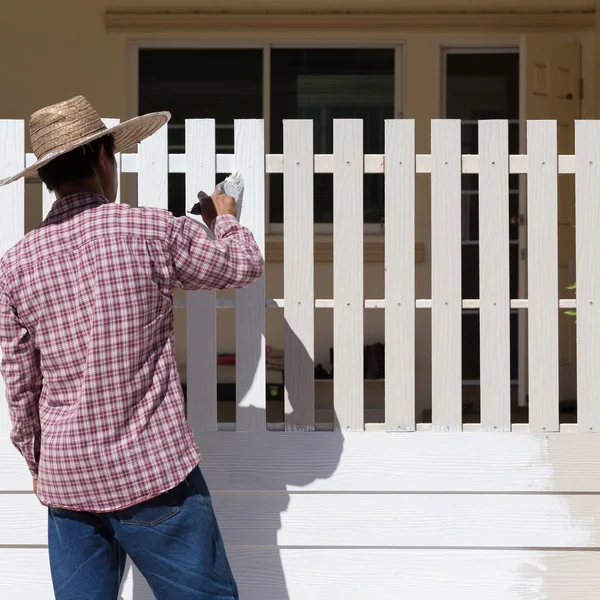 Worker painted white fence with brush