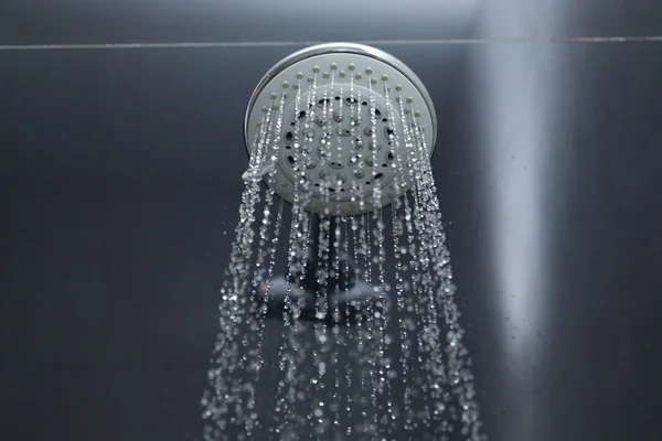 Shower head in bathroom with water drops flowing