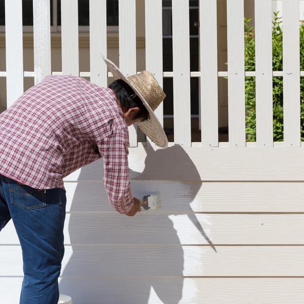 Worker painted white fence with brush