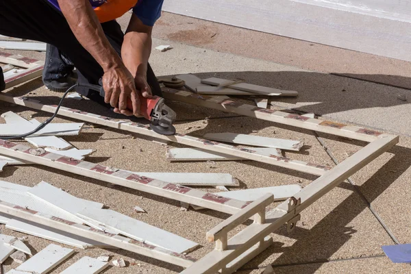 Man worker repairing steel fence with electric saw tool