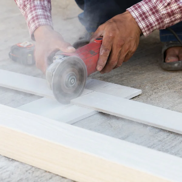 Carpenter hands using electric saw on wood at construction site