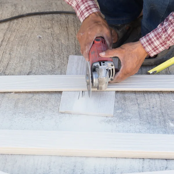 Carpenter hands using electric saw on wood at construction site