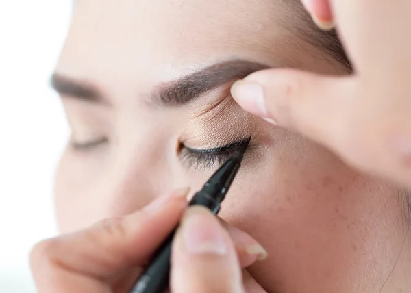 Makeup beauty with brush eye liner on pretty woman