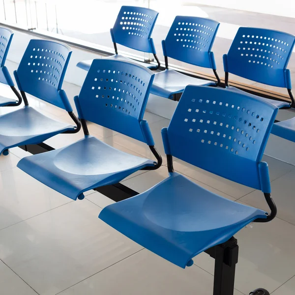 Customer waiting area with rows of blue seats in office