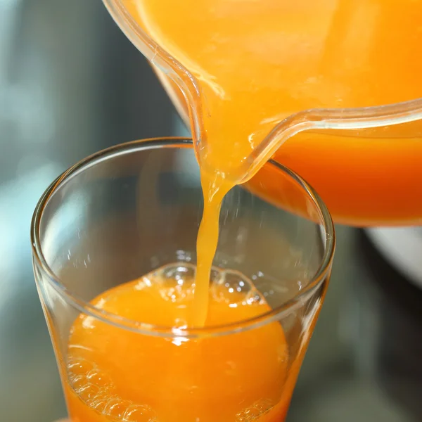 Fresh orange juice pouring from a jug into the glass