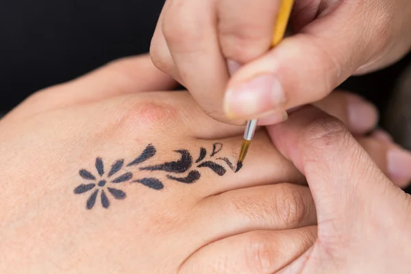 Body paint, artist used paintbrush drawing art on hand person