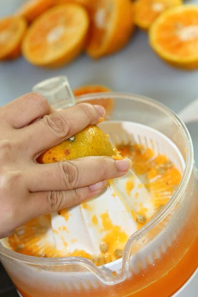 Orange fruit squeezed with woman hand in juicer machine