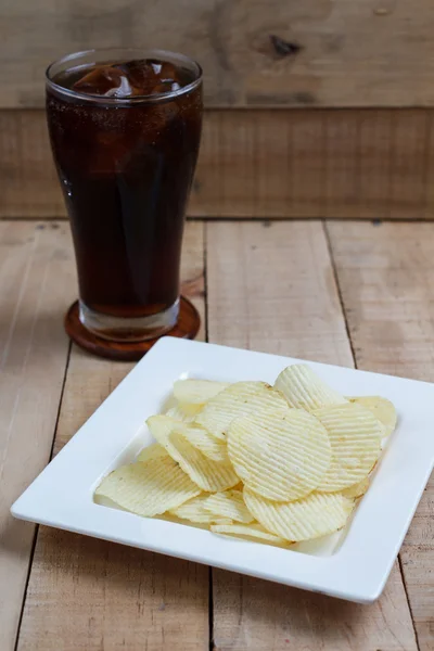 Potato chips and soft drink in glass on wood background, Selecti