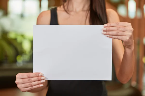 Young caucasian woman holding white sheet of paper