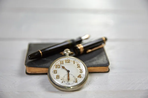 Antique fountain pen, old calendar and watch on a white wooden t